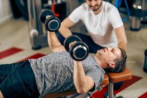 uomo fare allenarsi con allenatore nel un' Palestra foto