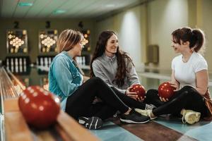 un' tre femmina amici avendo divertimento nel un' bowling vicolo foto