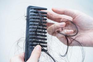 la donna asiatica ha problemi con la caduta dei capelli lunghi attaccata alla spazzola del pettine. foto