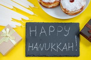 contento hanukkah. ebraico dolce sufganiyot su giallo sfondo. simboli di religioso giudaismo vacanza. ciambelle, candele e regalo. foto