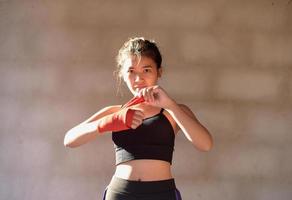 avvicinamento mani di femmina combattente indossare boxe fasciature preparazione. foto