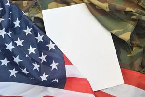 vuoto carta bugie su unito stati di America bandiera e piegato militare uniforme giacca. militare simboli concettuale sfondo bandiera e copia spazio foto
