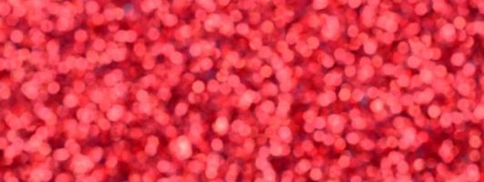 un' enorme quantità di rosso decorativo paillettes. sfocato sfondo Immagine con brillante bokeh luci a partire dal piccolo elementi quello riflettere leggero nel un' casuale ordine foto