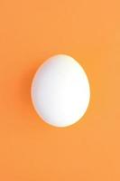 uno bianca Pasqua uovo su un' luminosa arancia sfondo foto