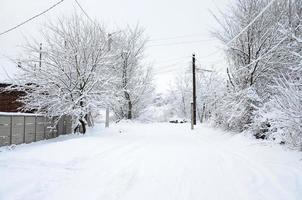 un' rustico inverno paesaggio con alcuni vecchio case e un' ampio autostrada coperto con un' di spessore strato di neve foto