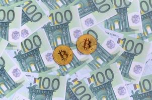 d'oro fisico bitcoin è bugie su un' impostato di verde monetario denominazioni di 100 euro. un' lotto di i soldi le forme un infinito mucchio foto