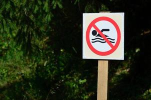 un' pilastro con un' cartello denotando un' bandire su nuoto. il cartello Spettacoli un' barrato galleggiante persona foto