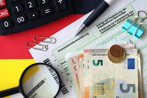 Tedesco reddito imposta ritorno modulo con penna e europeo Euro i soldi fatture bugie su bandiera vicino su. contribuenti nel Germania utilizzando Euro moneta per pagare le tasse foto