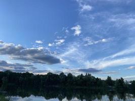 bellissimo tramonto su il lago. tramonto riflessa nel il acqua - blu e arancia cielo con nuvole e alberi nel silhouette foto