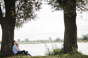 amorevole giovane coppia siamo abbracciare e sorridente all'aperto vicino il lago su soleggiato giorno. amore e tenerezza, datazione, romanza, famiglia concetto. foto