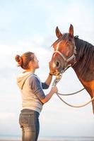 giovane ragazza adolescente allegra accarezzando il naso del cavallo marrone. immagine all'aperto. foto