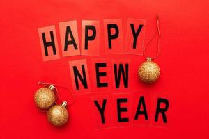 il iscrizione contento nuovo anno con brillante d'oro Natale giocattolo palle su un' rosso sfondo foto