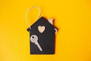 poco giocattolo Casa con un' chiave su un' arancia sfondo. foto