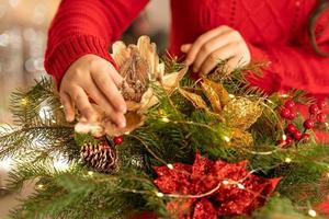 ragazza raccoglie un' Natale mazzo di abete rami, fiori e Natale albero decorazioni foto