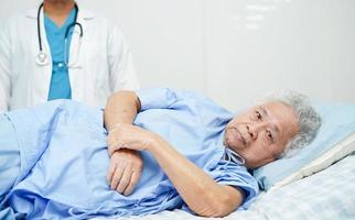 medico che si prende cura, aiuta e incoraggia il paziente asiatico anziano della donna anziana nell'ospedale della clinica. foto