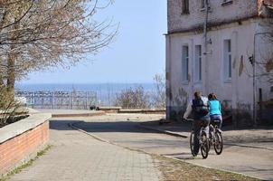 un' giovane coppia di bikers cavalcata attraverso vuoto strade durante chiaro tempo atmosferico. il tipo e il ragazza partire su biciclette foto