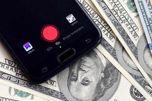 Kharkov. Ucraina - Maggio 17, 2022 smartphone schermo con tic toc App e lotto di centinaio dollaro fatture. attività commerciale e sociale networking concetto foto