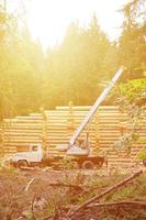 il processi di edificio un' di legno Casa a partire dal di legno travi di cilindrico forma. gru nel Lavorando condizione foto