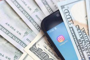 Kharkov. Ucraina - Maggio 17, 2022 smartphone schermo con instagram App e lotto di centinaio dollaro fatture. attività commerciale e sociale networking concetto foto