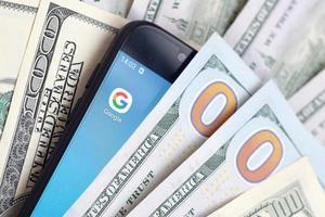 Kharkov. Ucraina - Maggio 17, 2022 smartphone schermo con Google App e lotto di centinaio dollaro fatture. attività commerciale e sociale networking concetto foto