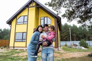 contento famiglia nel il cortile di un incompiuto Casa - Acquista di un' villetta, mutuo, prestito, trasloco, costruzione foto