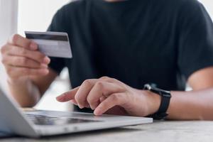 in linea shopping e-commerce o Internet bancario concetto.uomo mano Tenere credito carta e utilizzando laptop.business finanza pagamento e contabilità. foto