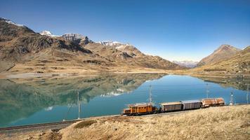 piccolo nolo treno su rotaie vicino un' alto montagna lago foto