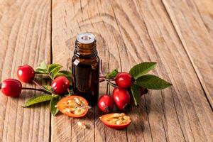 bicchiere medico bottiglia con un' contagocce di essenziale masoa o rosa canina seme essenza con fresco frutta su un' di legno sfondo. spa. aromaterapia. foto