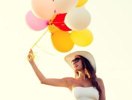 giovane donna sorridente in occhiali da sole con palloncini foto
