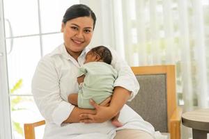 neonato bambino di un mese addormentato bene, senza preoccupazioni su il caldo La madre di il petto. giovane madre coccole adorabile infantile innocenza dopo nascita su braccia. concetto di genitorialità, maternità, adozione. foto