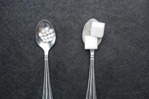 confrontando artificiale dolcificante fra crudo dolce su un' argento cucchiaio foto