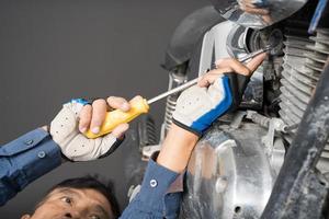 persone siamo riparazione un' motociclo uso un' chiave inglese e un' Cacciavite per opera foto