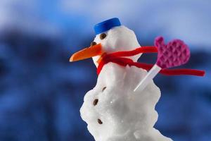 piccolo pupazzo di neve di Natale felice con guanti rosa all'aperto. stagione invernale.