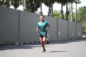 giovane asiatico ragazzo riscaldamento su per jogging nel il mattina foto