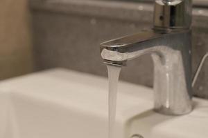 primo piano del rubinetto con acqua che scorre foto