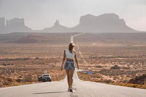 posteriore Visualizza di donna a piedi su strada principale in direzione monumento valle durante estate foto