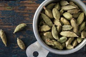 verde cardamomo baccelli nel un' misurazione tazza foto