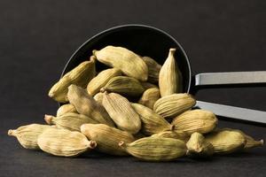 verde cardamomo baccelli rovesciato a partire dal un' cucchiaino foto