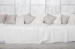 molti cuscini menzogna su il divano, quale è coperto con un' grande felpa velo contro il sfondo di un' marmo parete foto