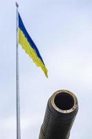 gruppi di antico militare pistole contro il sfondo di il stato bandiera di Ucraina. museruola freno di un artiglieria pistola. soleggiato mattina cielo. chiamata per fermare violenza concetto. ucraino bandiera. foto