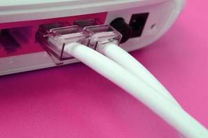 il Internet cavo spine siamo collegato per il Internet router, quale bugie su un' luminosa rosa sfondo. elementi necessario per Internet foto