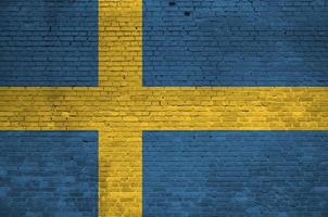 Svezia bandiera raffigurato nel dipingere colori su vecchio mattone parete. strutturato bandiera su grande mattone parete opere murarie sfondo foto