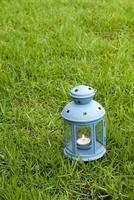 lanterna blu, con candela accesa all'interno, sull'erba verde foto