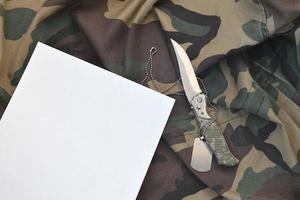 vuoto carta con coltello e esercito cane etichetta bugie su camuffare militare uniforme foto