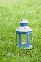 lanterna blu, con candela accesa all'interno, sull'erba verde foto