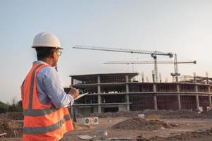 ingegnere asiatico che lavora al sito di un grande progetto di costruzione, gente della Tailandia, lavoro straordinario in cantiere foto