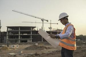 ingegnere asiatico che lavora al sito di un grande progetto di costruzione, gente della Tailandia, lavoro straordinario in cantiere foto