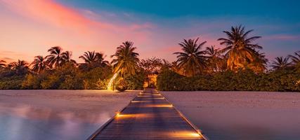 incredibile panorama al tramonto alle maldive. ville resort di lusso vista sul mare con luci a led soffuse sotto il cielo colorato. bel cielo al crepuscolo e nuvole colorate. bellissimo sfondo spiaggia per vacanze in vacanza foto