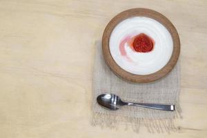 lo yogurt in tazza di legno ha la fragola isolata foto