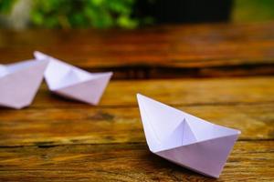 origami, bianca carta barca isolato su un' di legno pavimento. carta Barche significare a passeggio. sensazione di la libertà comando foto